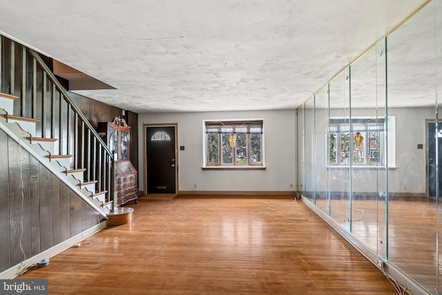 entryway with stairway, baseboards, plenty of natural light, and wood finished floors
