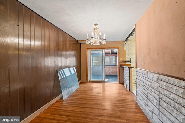 interior space with wooden walls, wood finished floors, and a chandelier