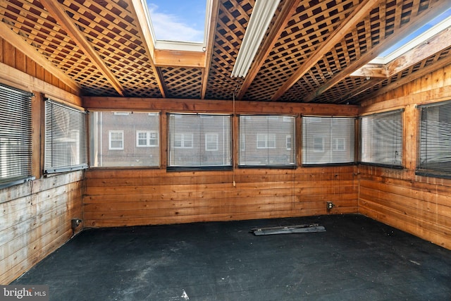 interior space with plenty of natural light, wood walls, and lofted ceiling with skylight