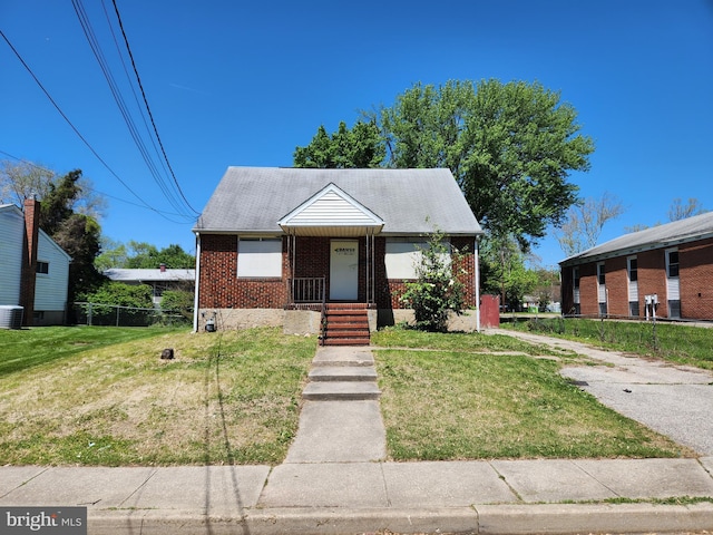 130 5th Ave, Baltimore, MD 21227 - view of front of property with brick siding, a front lawn, and central AC