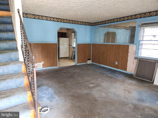 130 5th Ave, Baltimore, MD 21227 - unfurnished room with wainscoting, stairs, arched walkways, a textured ceiling, and wooden walls