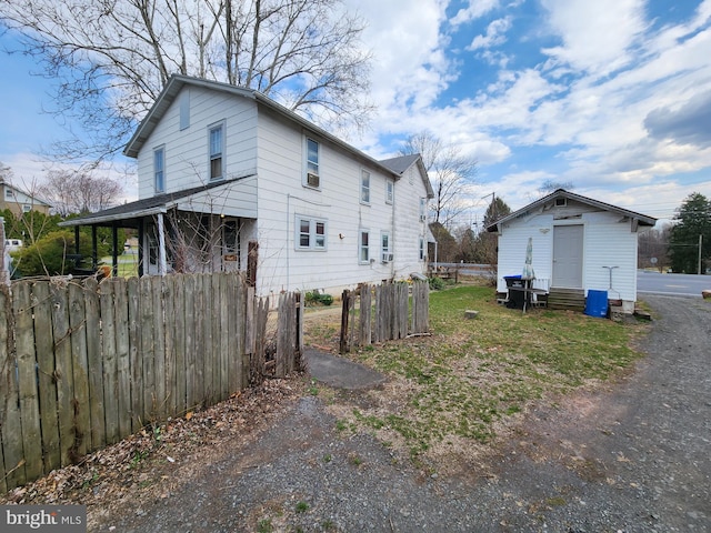 view of home's exterior featuring fence and an outbuilding