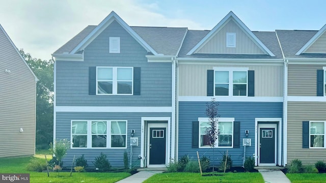 townhome / multi-family property featuring a front yard and roof with shingles