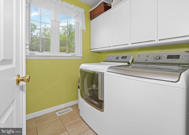 laundry area with light tile patterned floors, visible vents, baseboards, washer and clothes dryer, and cabinet space
