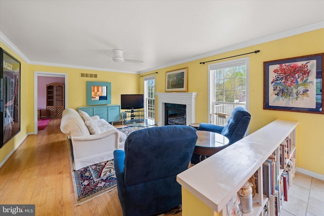 living area featuring visible vents, ornamental molding, ceiling fan, and a fireplace