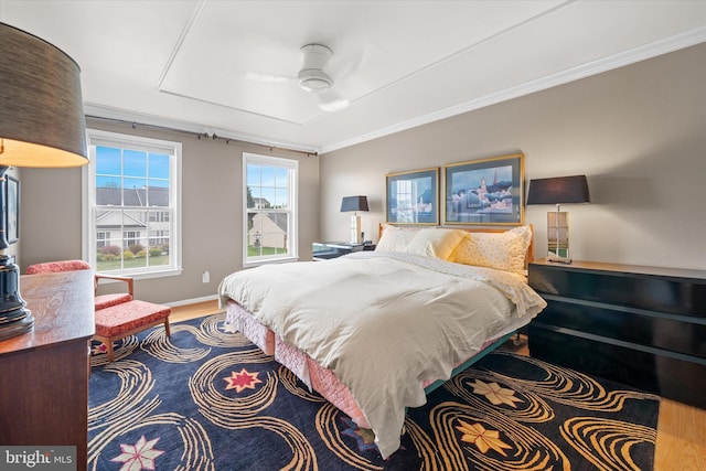 bedroom featuring baseboards, wood finished floors, and ornamental molding