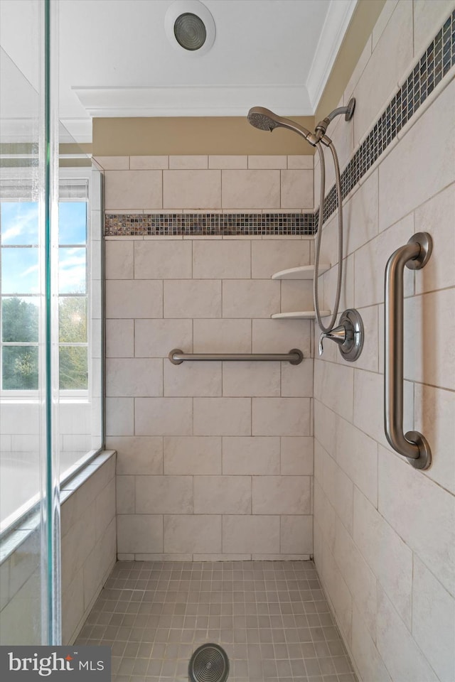 bathroom with a tile shower and crown molding