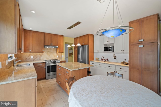 kitchen featuring under cabinet range hood, brown cabinetry, appliances with stainless steel finishes, and a sink