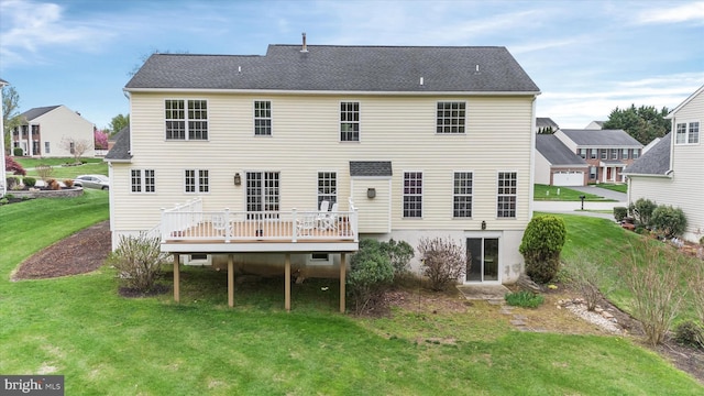back of property with a wooden deck, a yard, and roof with shingles