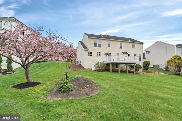 back of property with a lawn, a deck, and stairs
