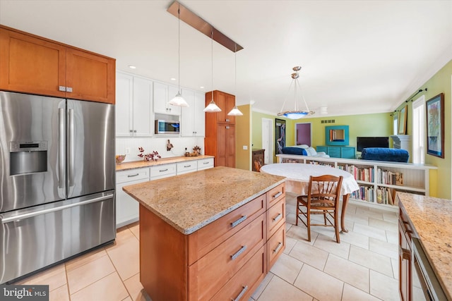 kitchen with light tile patterned floors, open floor plan, decorative light fixtures, and stainless steel appliances
