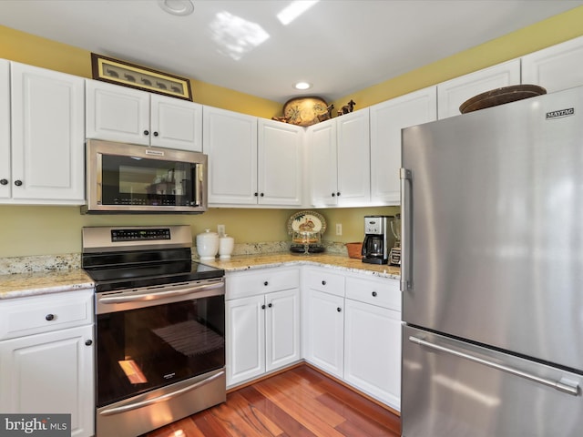 11 Spearpoint Ln, Hedgesville, WV 25427 - kitchen featuring appliances with stainless steel finishes, light stone countertops, wood finished floors, white cabinets, and recessed lighting