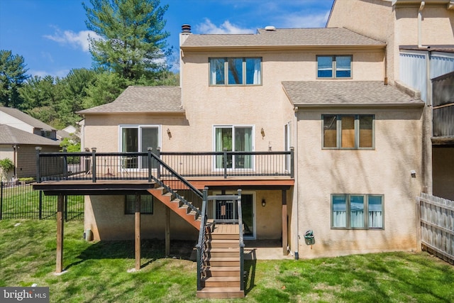 rear view of house with a lawn, a deck, stairway, fence, and stucco siding