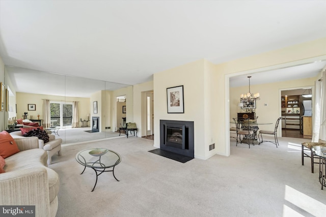 living area with visible vents, a fireplace with flush hearth, carpet, and an inviting chandelier