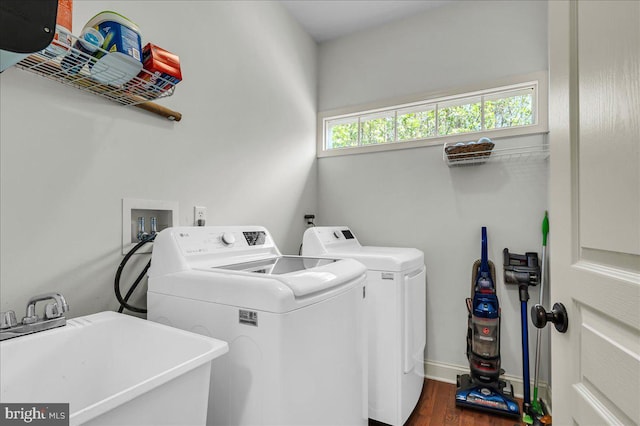clothes washing area featuring laundry area, a sink, baseboards, separate washer and dryer, and dark wood-type flooring