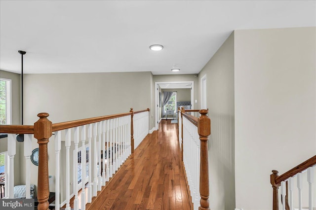 hall with a wealth of natural light, wood finished floors, and an upstairs landing