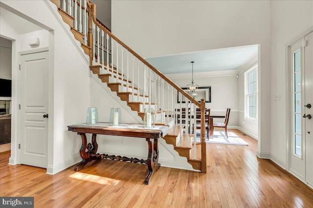 entryway featuring stairway, baseboards, light wood finished floors, an inviting chandelier, and ornamental molding