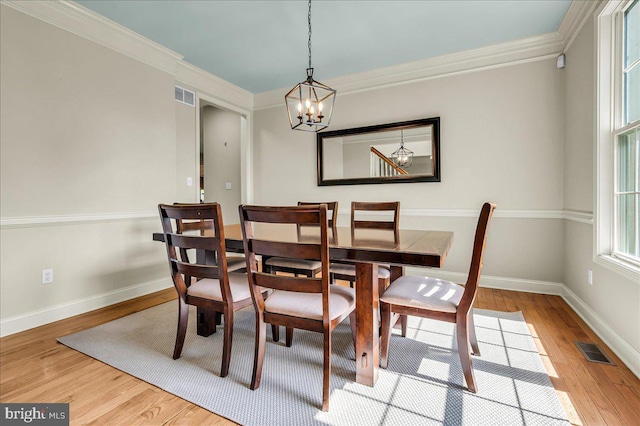 dining room with ornamental molding, a chandelier, wood finished floors, and visible vents