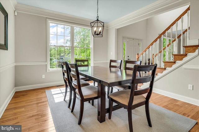 dining room with stairway, baseboards, light wood finished floors, an inviting chandelier, and ornamental molding