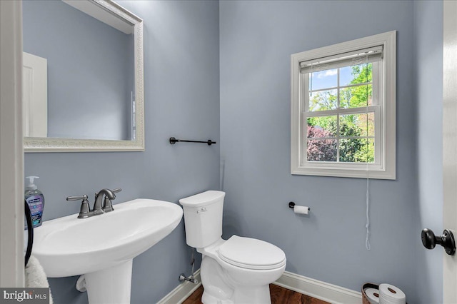 bathroom with toilet, baseboards, a sink, and wood finished floors