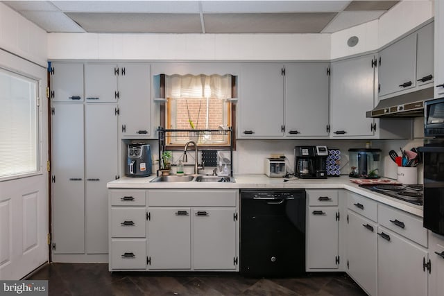 kitchen with a sink, light countertops, black appliances, and under cabinet range hood