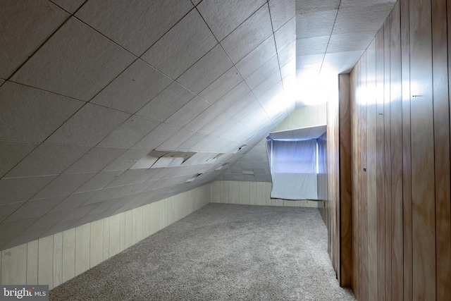 additional living space with carpet floors, wood walls, and vaulted ceiling