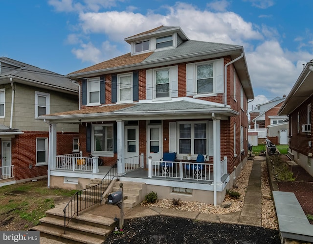 view of front of property featuring covered porch, a shingled roof, and brick siding