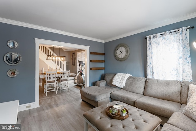 living room with baseboards, ornamental molding, wood finished floors, and a chandelier
