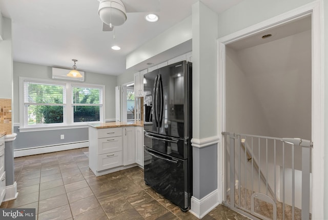 kitchen with a baseboard heating unit, white cabinetry, black fridge, and light countertops