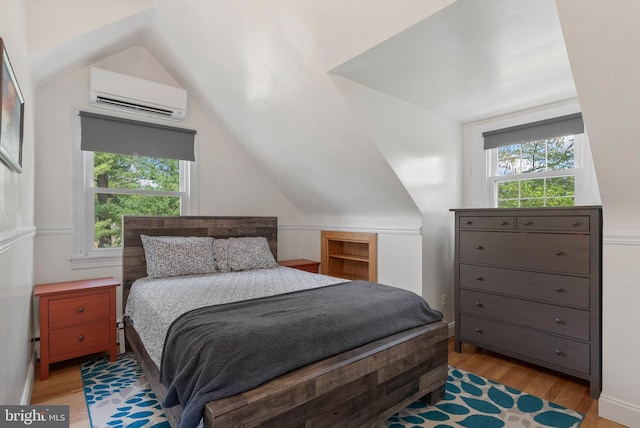 bedroom with lofted ceiling, a wall unit AC, light wood-style flooring, and multiple windows