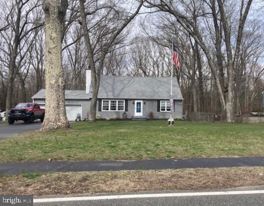 ranch-style home featuring a garage, a chimney, a front yard, and aphalt driveway