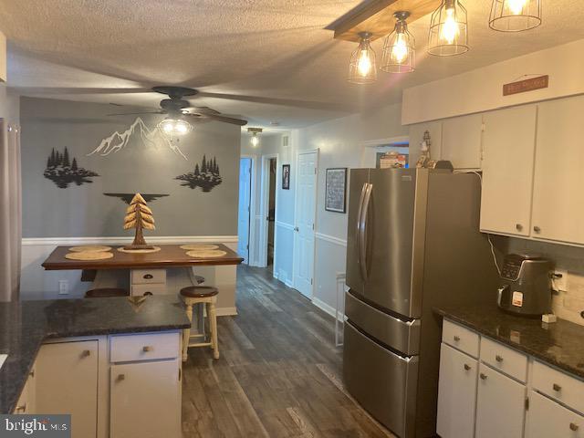 kitchen with white cabinets, a textured ceiling, dark wood finished floors, freestanding refrigerator, and a ceiling fan