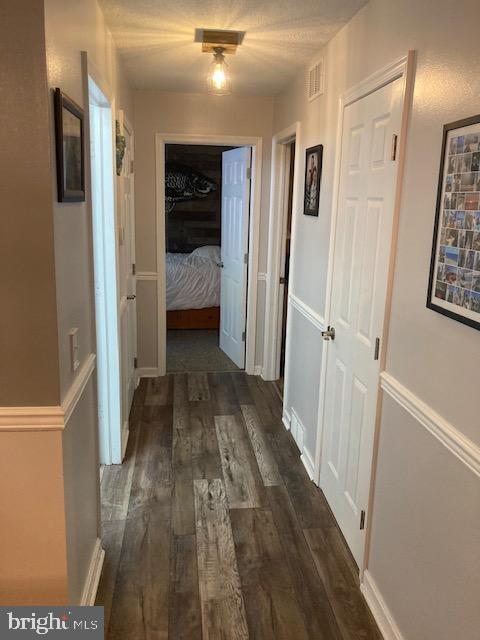 hall with visible vents and dark wood finished floors