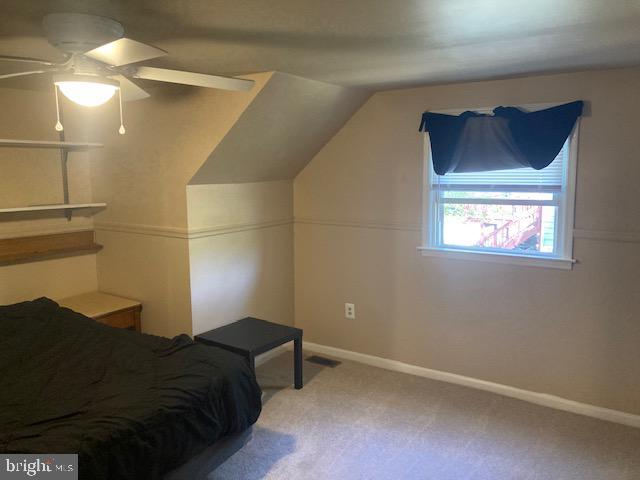 carpeted bedroom featuring baseboards, vaulted ceiling, ceiling fan, and visible vents