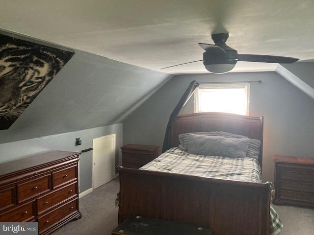carpeted bedroom with ceiling fan and vaulted ceiling