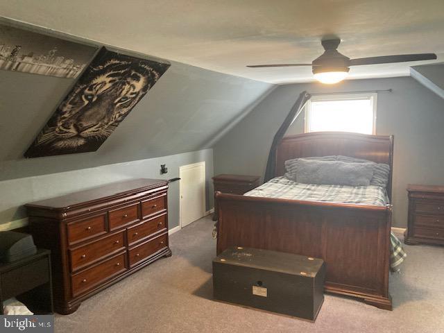 carpeted bedroom with ceiling fan and vaulted ceiling