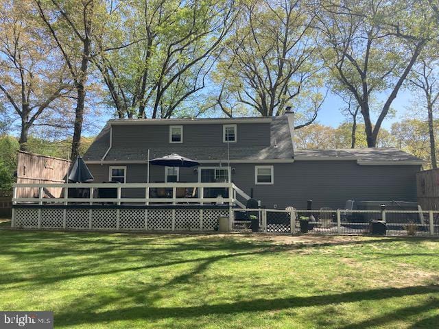 back of property featuring a chimney, fence, a yard, and a wooden deck