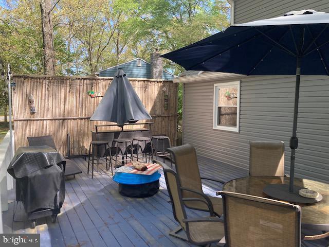 wooden terrace featuring outdoor dining space and area for grilling
