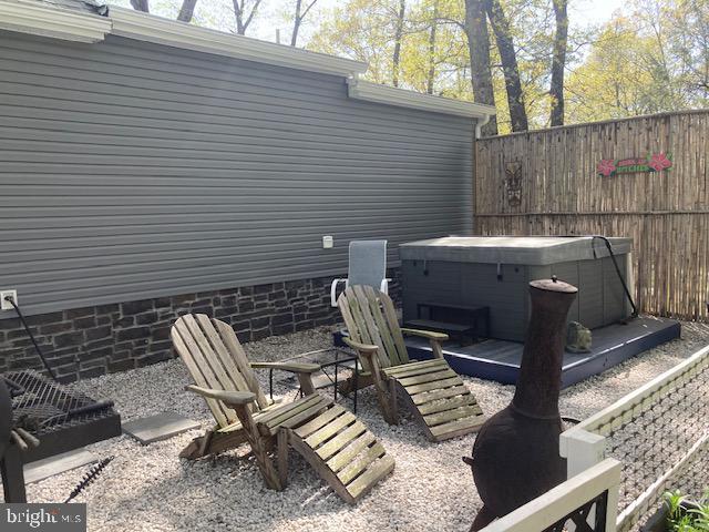 view of patio / terrace featuring fence, a wooden deck, and a hot tub