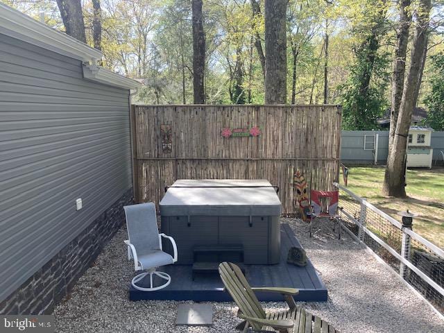 view of patio with a hot tub and fence
