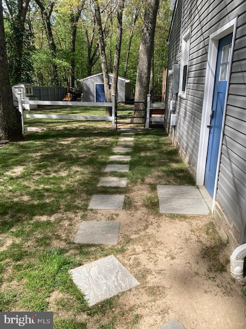 view of yard featuring fence, a gate, and an outdoor structure