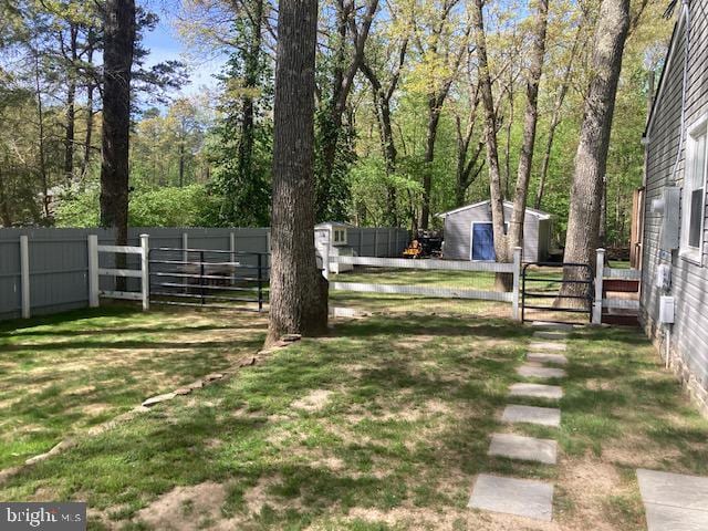 view of yard featuring an outdoor structure, a gate, a shed, and a fenced backyard