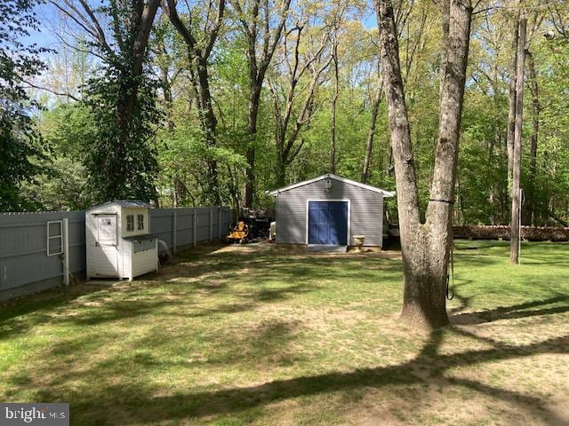 view of yard featuring an outdoor structure, a garage, a fenced backyard, and a storage shed