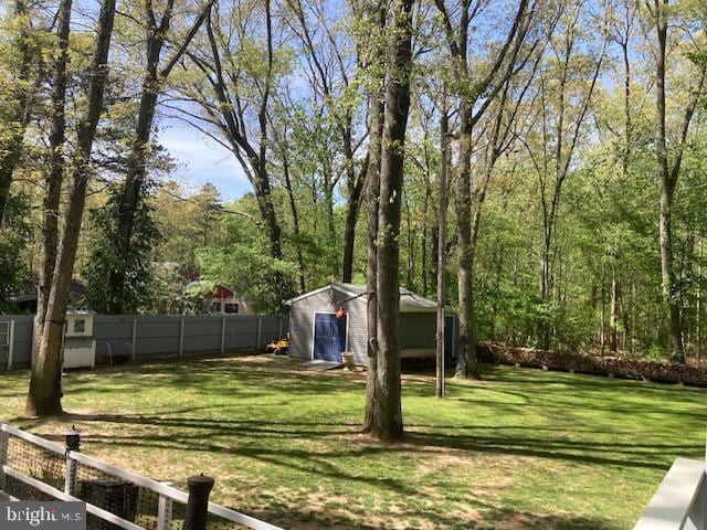 view of yard with a storage shed, fence, and an outbuilding