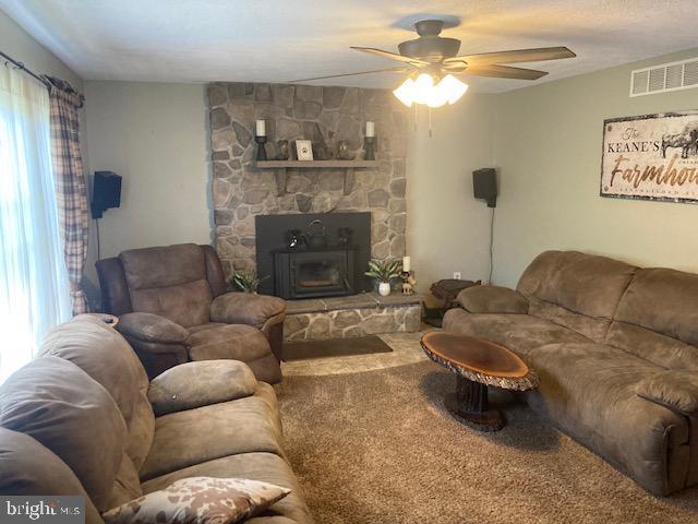 carpeted living room featuring a ceiling fan and visible vents