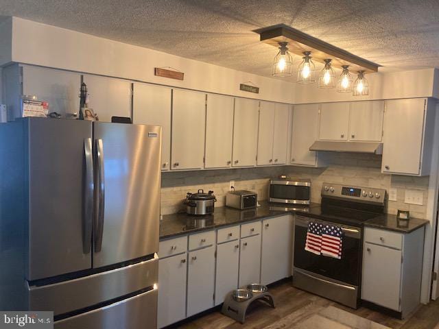 kitchen with white cabinets, dark countertops, appliances with stainless steel finishes, a textured ceiling, and tasteful backsplash