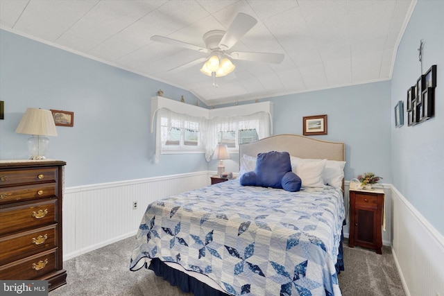 carpeted bedroom featuring crown molding, ceiling fan, and a wainscoted wall