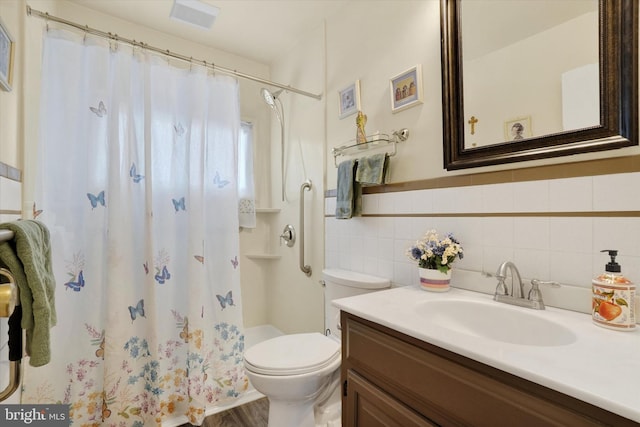 bathroom with vanity, toilet, tile walls, a shower stall, and visible vents