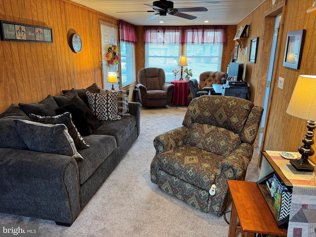 living area with carpet floors, a ceiling fan, and wood walls