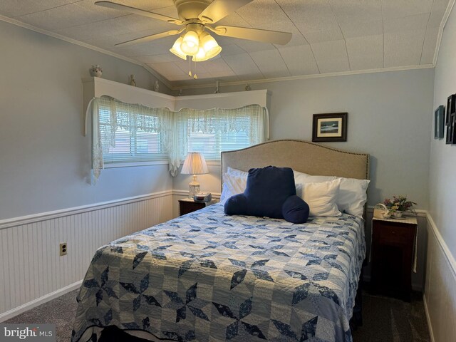 bedroom featuring carpet flooring, crown molding, ceiling fan, and a wainscoted wall